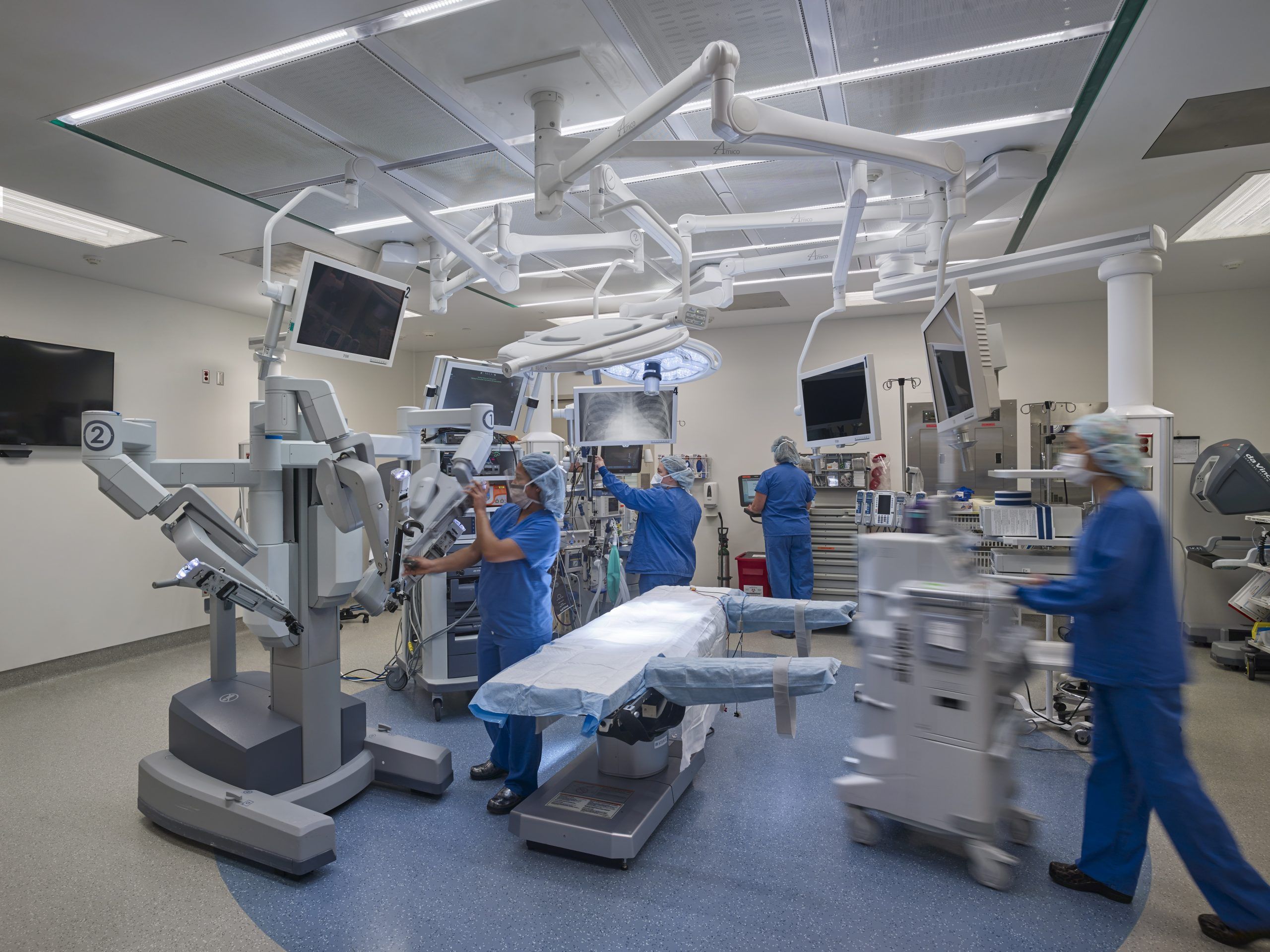 Medical staff in blue scrubs set up an operation room with robotics and x-ray capabilities