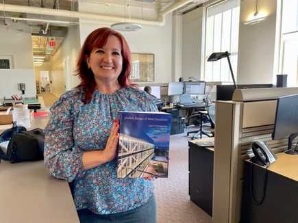 Angela Fante holding a steel structure textbook in Ballinger office