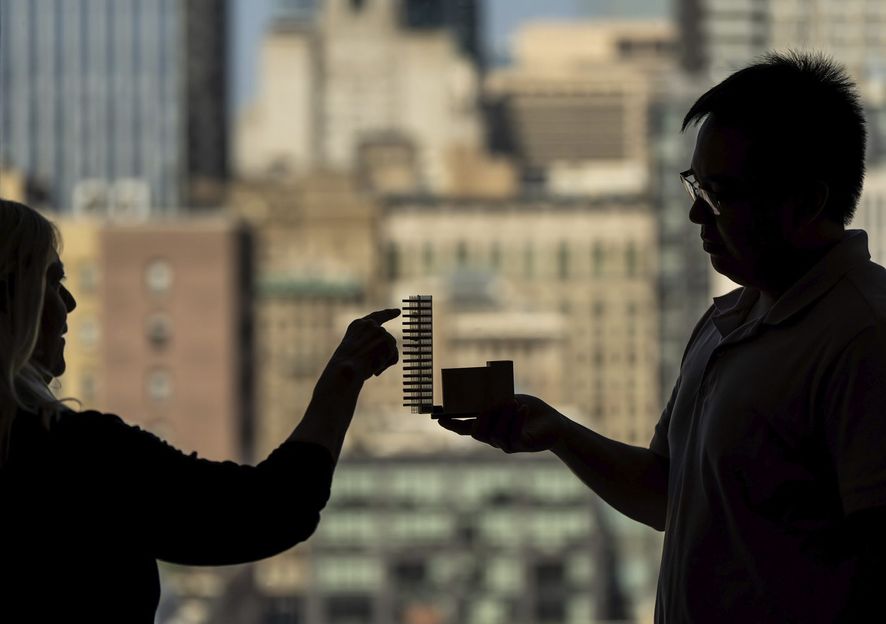 Silhouette of people looking at a small building model